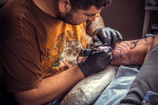Tattooist doing tattoo in studio./Tattoo specialist makes tattoo in tattoo studio.