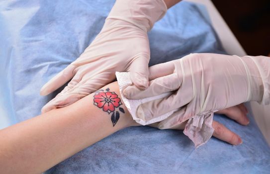 Tattoo specialist works in tattoo studio./Professional tattooist doing tattoo in tattoo studio.