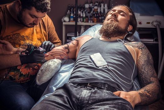 Professional tattooist makes tattoo in studio.