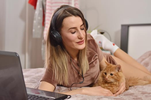 Beautiful caucasian woman listen music wih her red citten in bedroom