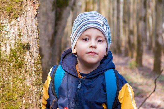 portrait of a cute boy in the park in spring. A boy in a hat on the street. Walk, play and have fun. Emotions, joy. Portrait of a child. Spring