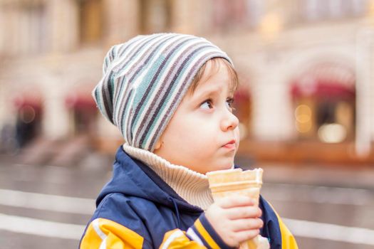 portrait of a cute boy in the park in spring. A boy in a hat on the street. Walk, play and have fun. Emotions, joy. Portrait of a child. Spring