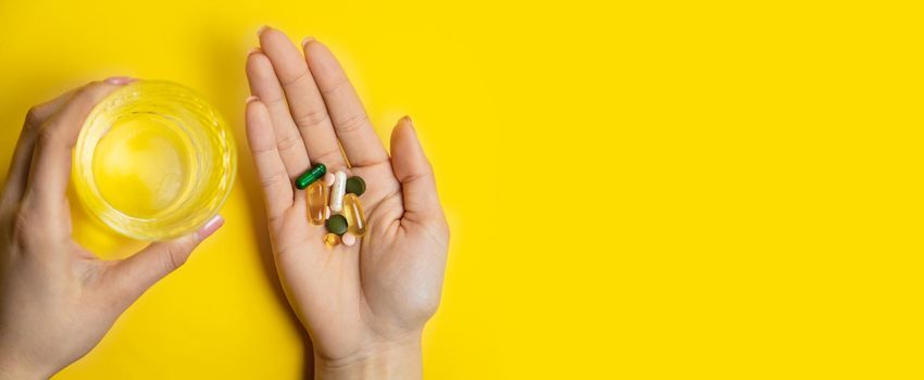 hands on yellow background, pills water cure virus.