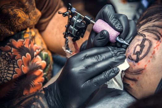 Master makes tattoo pictures in studio./Professional tattooist doing tattoo in salon.