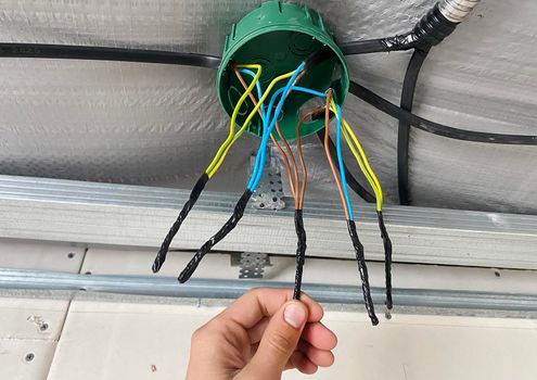 Electrical wiring of the junction box, installation, twisting of the box by an electrician. Selective focus.