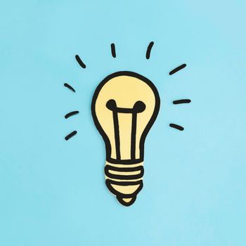 illuminated paper cutout yellow light bulb blue background