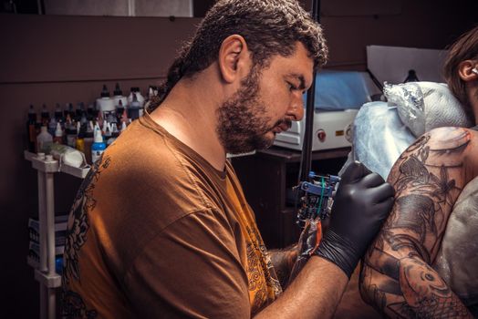 Professional tattooist works in tatoo salon/Tattooist showing process of making a tattoo in tattoo studio.