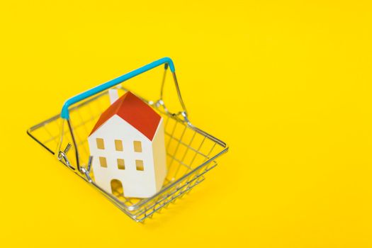 overhead view house model inside shopping cart against yellow background