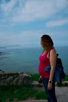 pregnant young woman posing by the sea,smiling with happiness