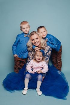 Studio portrait of happy smiling family of five posing and looking at camera together. Cheerful father embracing his children. Isolate on blue.