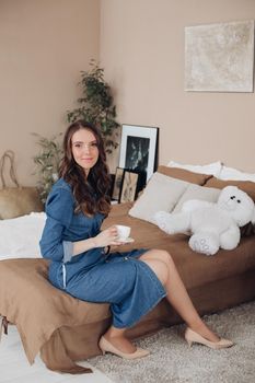 Portrait of gorgeous brunette young woman in casual denim dress embracing her lovely son in denim shirt on the bed. Family and motherhood concept.