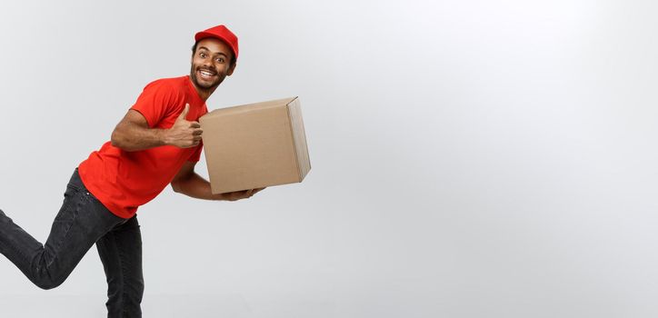 Delivery Concept - Handsome African American delivery man rush running for delivering a package for customer. Isolated on Grey studio Background. Copy Space