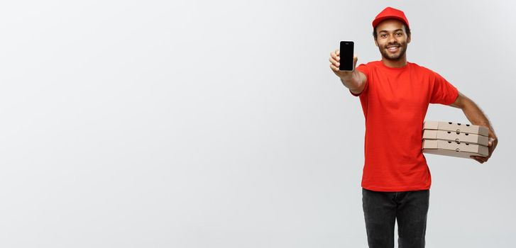 Delivery Concept - Portrait of Handsome African American delivery man or courier with pizza box showing mobile phone on you to check the order. Isolated on Grey studio Background. Copy Space