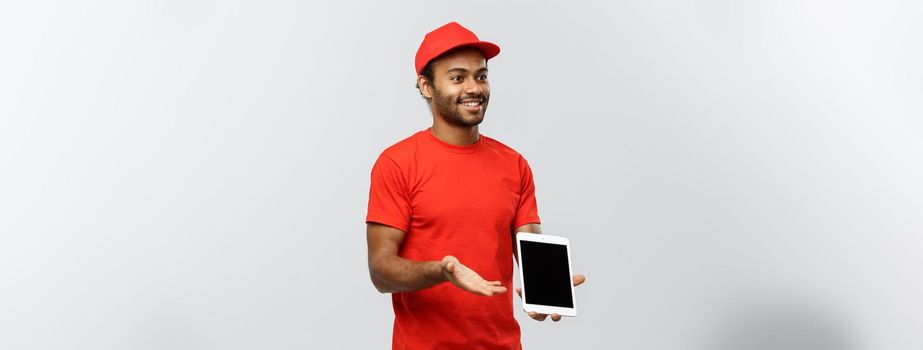 Delivery Concept - Portrait of Handsome African American delivery man or courier showing tablet on you to check the order. Isolated on Grey studio Background. Copy Space