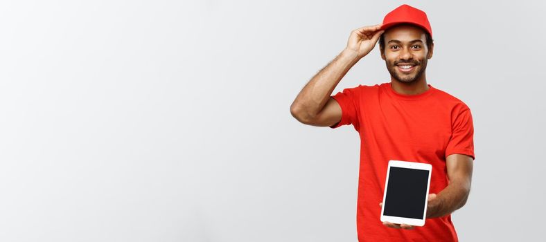 Delivery Concept - Portrait of Handsome African American delivery man or courier showing tablet on you to check the order. Isolated on Grey studio Background. Copy Space