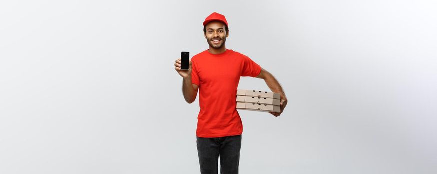 Delivery Concept - Portrait of Handsome African American delivery man or courier with pizza box showing mobile phone on you to check the order. Isolated on Grey studio Background. Copy Space