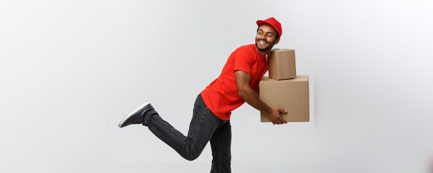 Delivery Concept - Handsome African American delivery man rush running for delivering a package for customer. Isolated on Grey studio Background. Copy Space