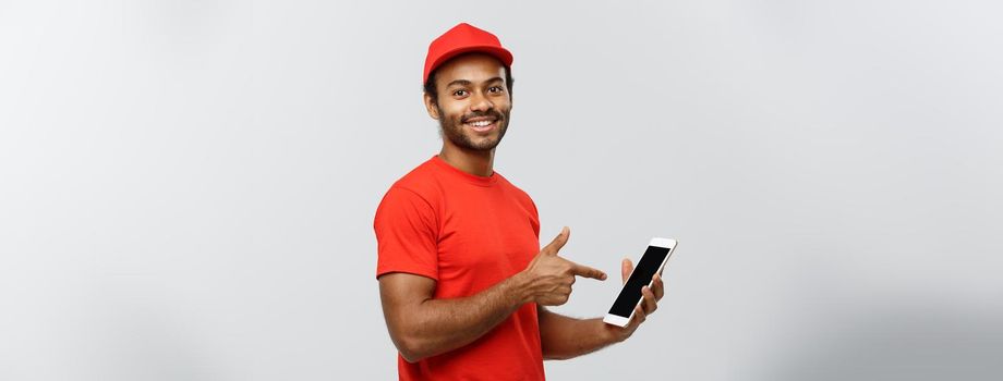 Delivery Concept - Portrait of Handsome African American delivery man or courier showing tablet on you to check the order. Isolated on Grey studio Background. Copy Space