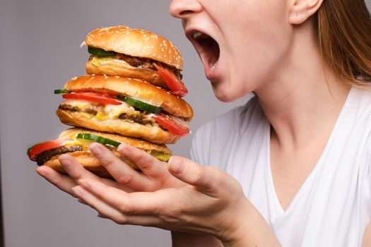 girl with a burger in his hands opened her mouse to eat a big portion of hamburger