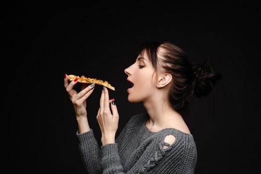 Close up of hungry girl with opened mouth, holding and eating pizza. Pretty woman pizza eating tasty pizza with tomato and meal. Concept of fast food.