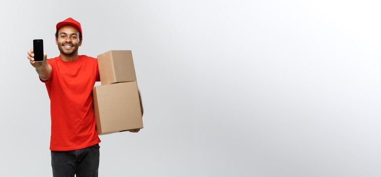 Delivery Concept - Portrait of Handsome African American delivery man or courier with box showing mobile phone on you to check the order. Isolated on Grey studio Background. Copy Space