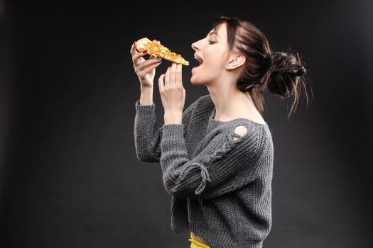 Close up of hungry girl with opened mouth, holding and eating pizza. Pretty woman pizza eating tasty pizza with tomato and meal. Concept of fast food.