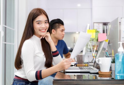 Business women smileing holding document paper chart sitting at home office. Group asian business people using computer PC  at office. Business at home concept. Start-up