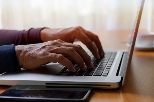 Close up businessman using laptop computer at home. Close up male hands typing on laptop keyboard in office. Man hands using laptop keyboard. Close-ups of technology in use concept.