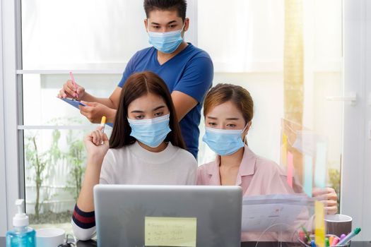 Asian Business Team Meeting Brainstorming Business start up working at Private Home Office social distancing among Coronavirus outbreak New generation business people meeting analysis work from laptop