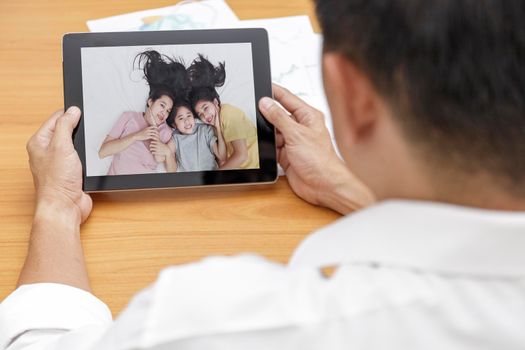 Businessman speak with family on tablet via internet video conference at office. Covid-19, coronavirus outbreak man speak with his family by tablet.