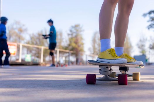 Close-up Asian women surf skate or skateboard outdoors on beautiful morning. Happy young women play surf skate at ramp park on morning time. Close up Asian women leg wear sneaker play surf skate on public park. Sport concept