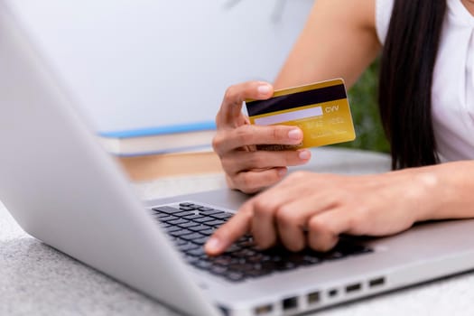 Young woman holding credit card and using laptop computer. Women working at home. Online shopping, e-commerce, internet banking, spending money, working from home concept. Technology shopping online concept.