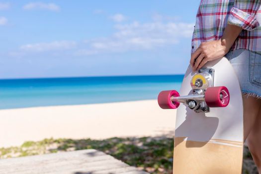 Close up young women hold surf skate board with beach background. Women stand with surf skate relax and enjoy with tropical beach with copy space