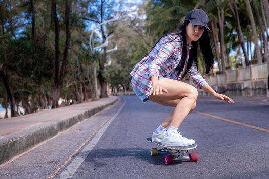 Young asian women play surf skate board at beach road outdoors on morning. Happy women play surfskate board on beach road . Sport activity lifestyle concept