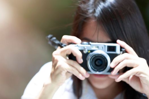 Blur focus of trvel women long hair use camera shot of something. Blur Asian women use small camera shot. Blur portrait of young woman holding a camera with black reflect in a front lens. bakcground concept