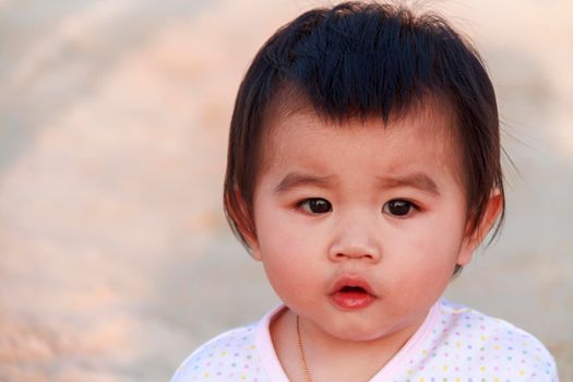 Close up portrait little girl. Cute adorable asian little girl play in park with sun ray background. Happy baby girl play in outdoor park. Close up and soft focus baby gril.