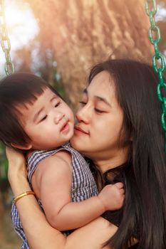 Portrait of happy Asian mother and daughter. Asian woman and little toddler girl in the playground park. Happy family playing together at playground park