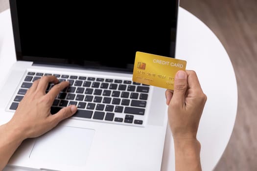 Young woman holding credit card and using laptop computer. Women working at home. Online shopping, e-commerce, internet banking, spending money, working from home concept. Technology shopping online concept.
