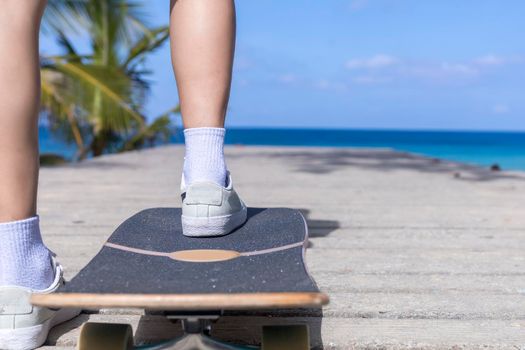Close up Young asian women play surf skate board at beach road outdoors on morning. Happy women play surfskate board on beach road . Sport activity lifestyle concept