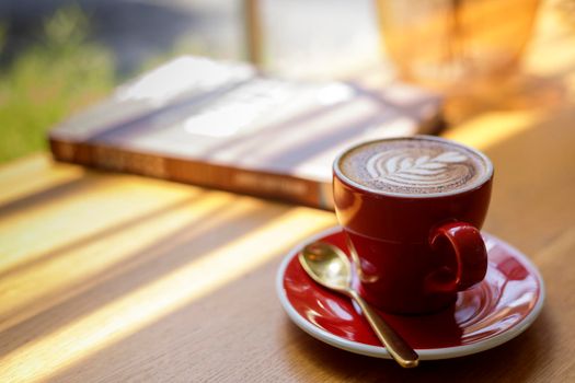 Close up hot art Latte, cappuccino Coffee in red cup on wooden table in Coffee shop blur background with bokeh image.