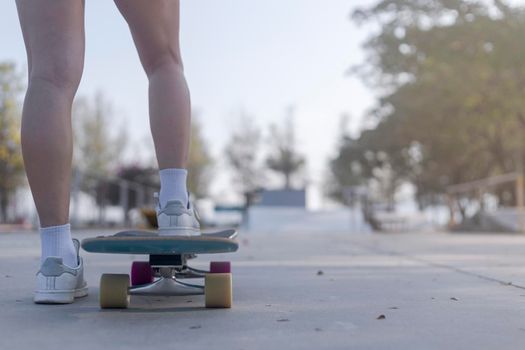 Close-up Asian women surf skate or skateboard outdoors on beautiful morning. Happy young women play surf skate at ramp park on morning time. Close up Asian women leg wear sneaker play surf skate on public park. Sport concept