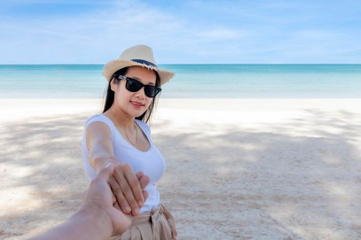 POV Point of view Follow me woman wear sunglasses leads boyfriend by hand to the sea, Looking camera. Back view of happy girl walking on beach. Couple holiday travel on beach. Summer vacation.
