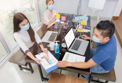 Asian small business start up multiracial working at Private Home Office social distancing among Coronavirus outbreak. Business people show and talking about document chart financial report. 
