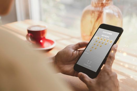 Customer service and Satisfaction concept ,Women hand hold smart phone choose the 5 star icon to give satisfaction in service. rating very impressed in coffeeshop.