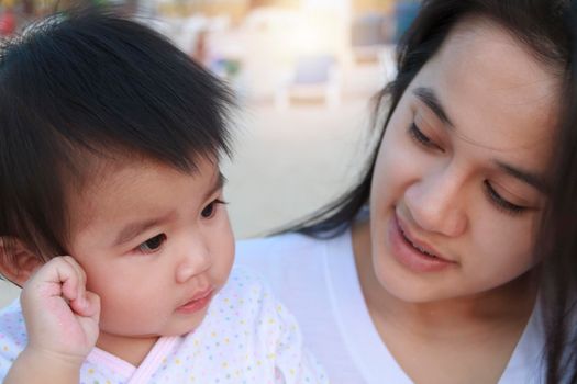 Close up Portrait of happy Asian mother and daughter. Asian woman and little toddler girl in the playground park. Happy family playing together at playground park