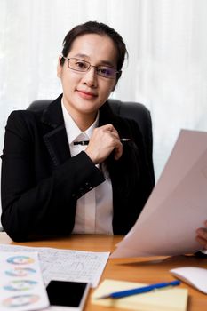 Business women smileing wear glasses holding document paper chart sitting at office. business people using computer PC  at office. Business at home concept.
