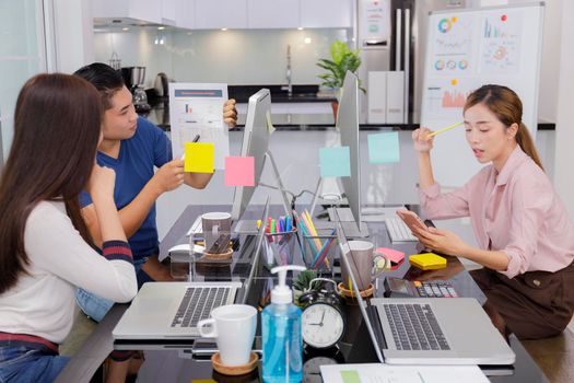 Asian small business startup multiracial working at Private Home Office social distancing among Coronavirus outbreak. Business people show and talking about document chart financial report. Business women use smartphone talking with customer.