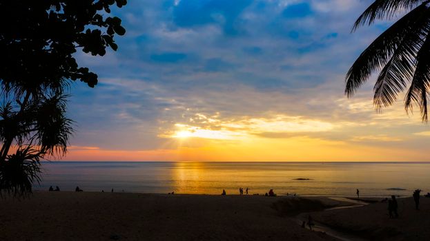Silhouettes of group of people during the sunset in Seaside beach. Beautiful sunset over the sea with silhouettes happy group of people relax. Holiday and summer concept