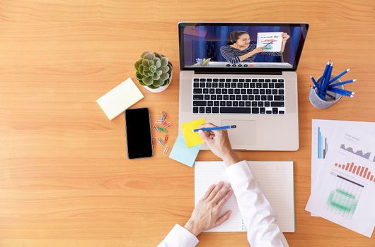 Top view Businessman and businesswoman analysis financial chart with videoconference online meeting. Hand of businesswomen using laptop meeting with diverse colleagues. Covid-19 working from home. 