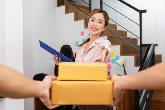 Delivery man delivering package to homeowner. Woman accepting a delivery of boxes from deliveryman. Hand of delivery man sent box package to women. Delivery concept.